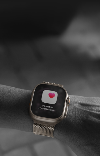 Iemand met een Apple Watch Ultra 3 om de pols, melding over mogelijk hoge bloeddruk op display